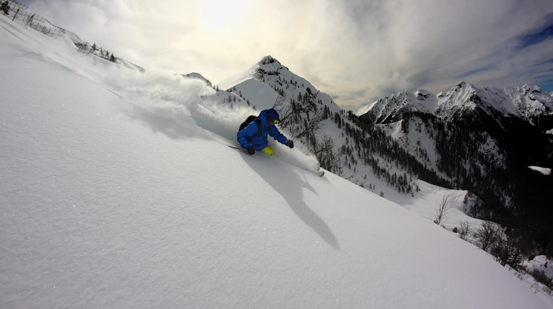 Una curva in neve fresca sul versante, con la valle alle spalle